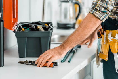 image of handyman with his toolbox on the bench reaching for some pliers