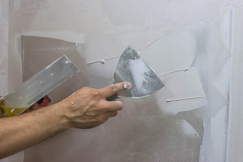 image of a trowel applying some plaster to a un painted wall